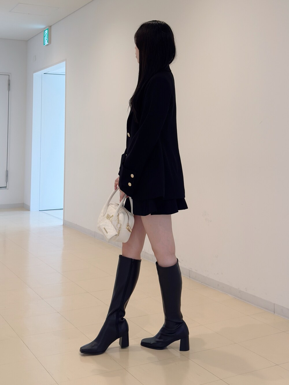 ブラック系のテーラードジャケット、グレー系のニット/セーター、ブラック系のスカートを着用したレディースの秋コーディネートの3枚目の写真