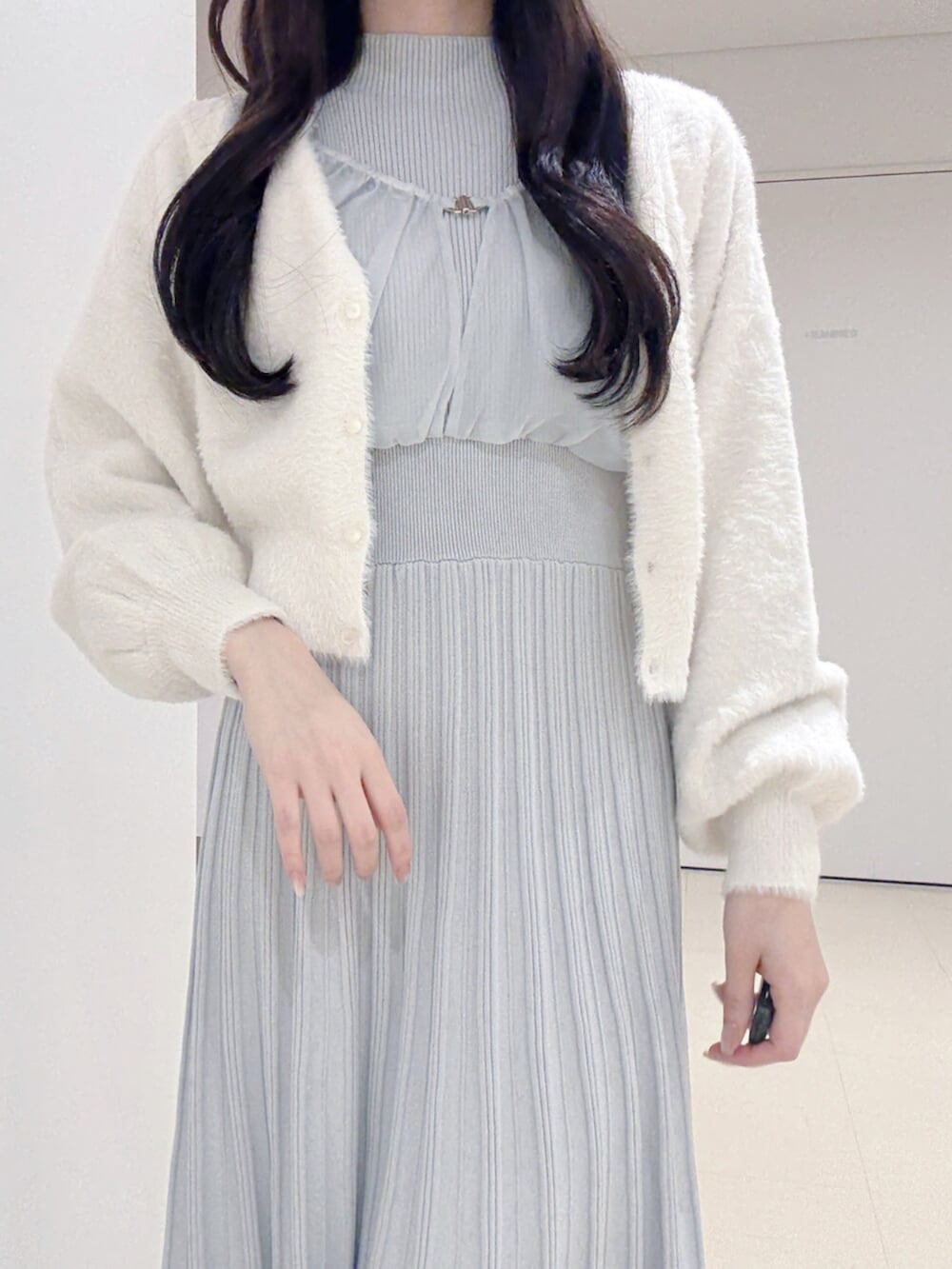 ブラック系のハンドバッグ、ホワイト系のブーツ、ホワイト系のカーディガン/ボレロを着用したレディースの冬コーディネートの5枚目の写真