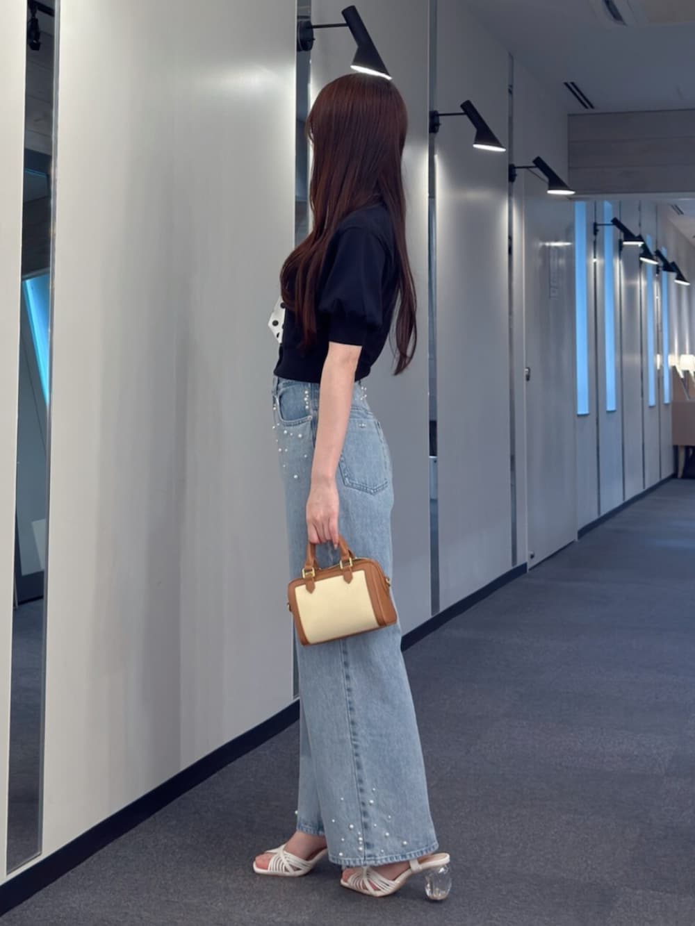 ブラウン系のハンドバッグ、ブルー系のデニムパンツ、ホワイト系のサンダルを着用したレディースの夏コーディネートの3枚目の写真