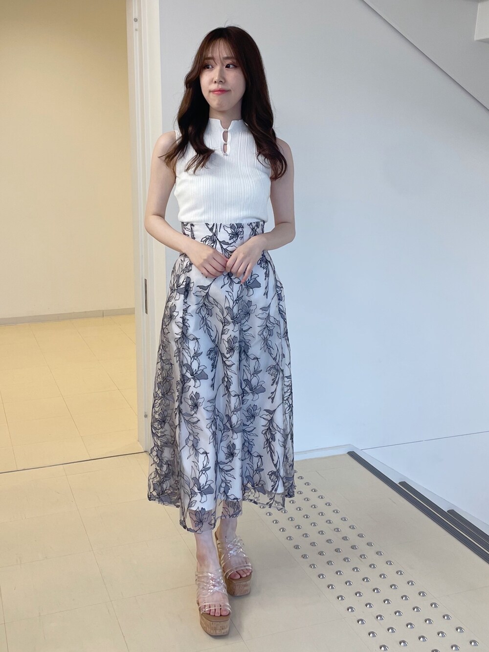 ホワイト系のニット/セーター、グレー系のスカート、その他のサンダルを着用したレディースの春コーディネートの2枚目の写真