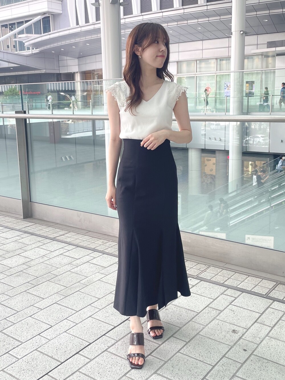 ホワイト系のニット/セーター、ブラック系のスカート、ブラウン系のサンダルを着用したレディースの夏コーディネートの2枚目の写真