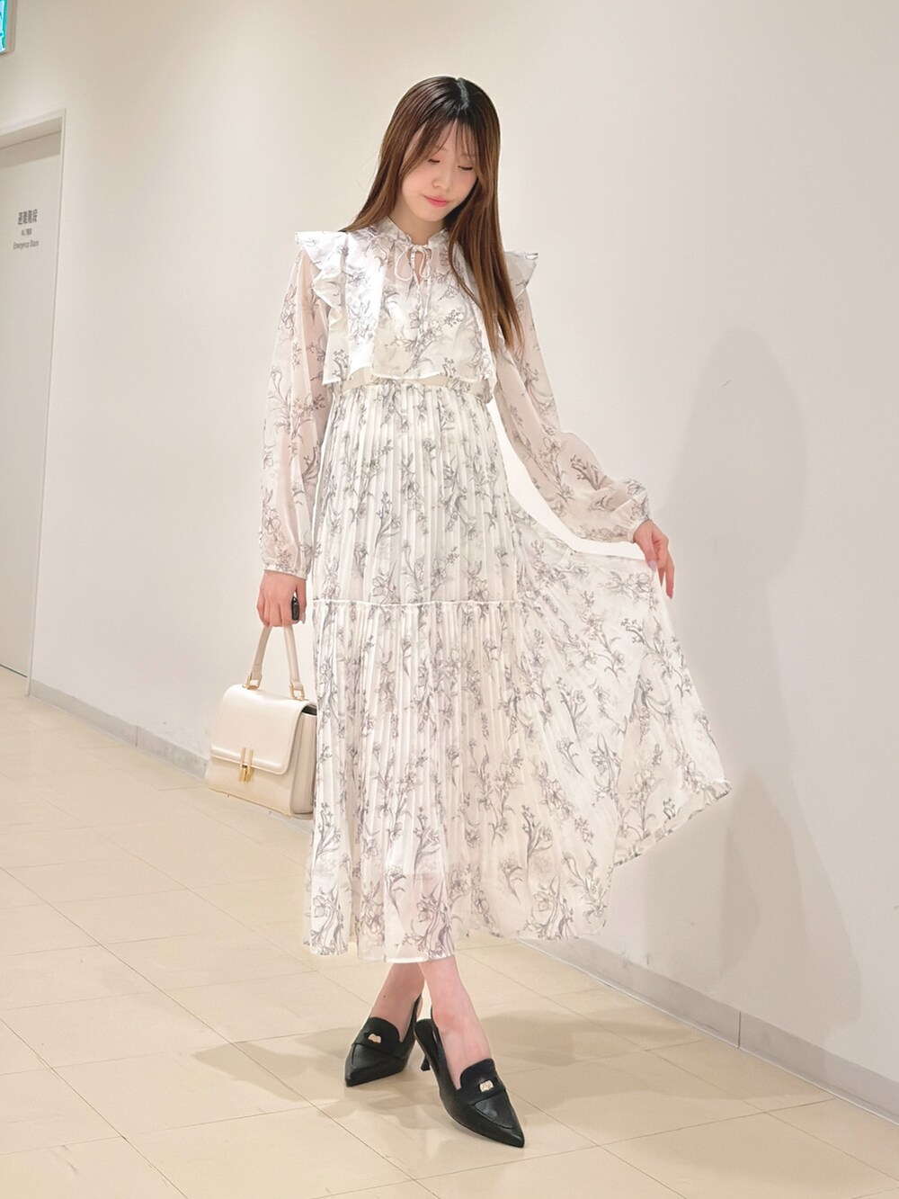 ホワイト系のワンピース、ホワイト系のハンドバッグ、ブラック系のパンプスを着用したレディースの春コーディネートの2枚目の写真