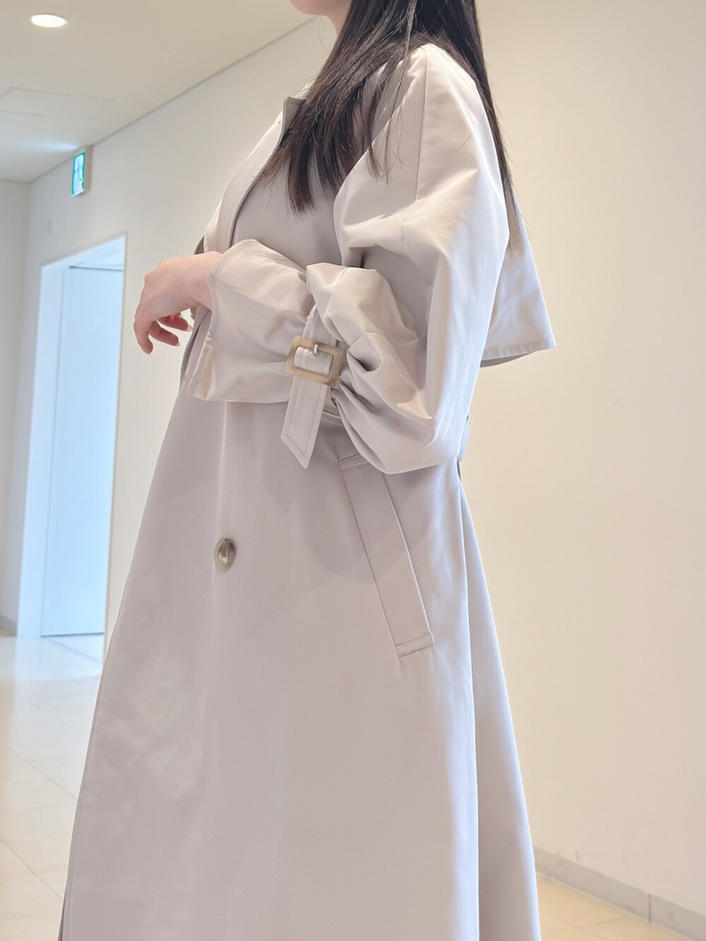 ベージュ系のトレンチコート、ホワイト系のニット/セーター、ブラック系のスカートを着用したレディースの春コーディネートの7枚目の写真