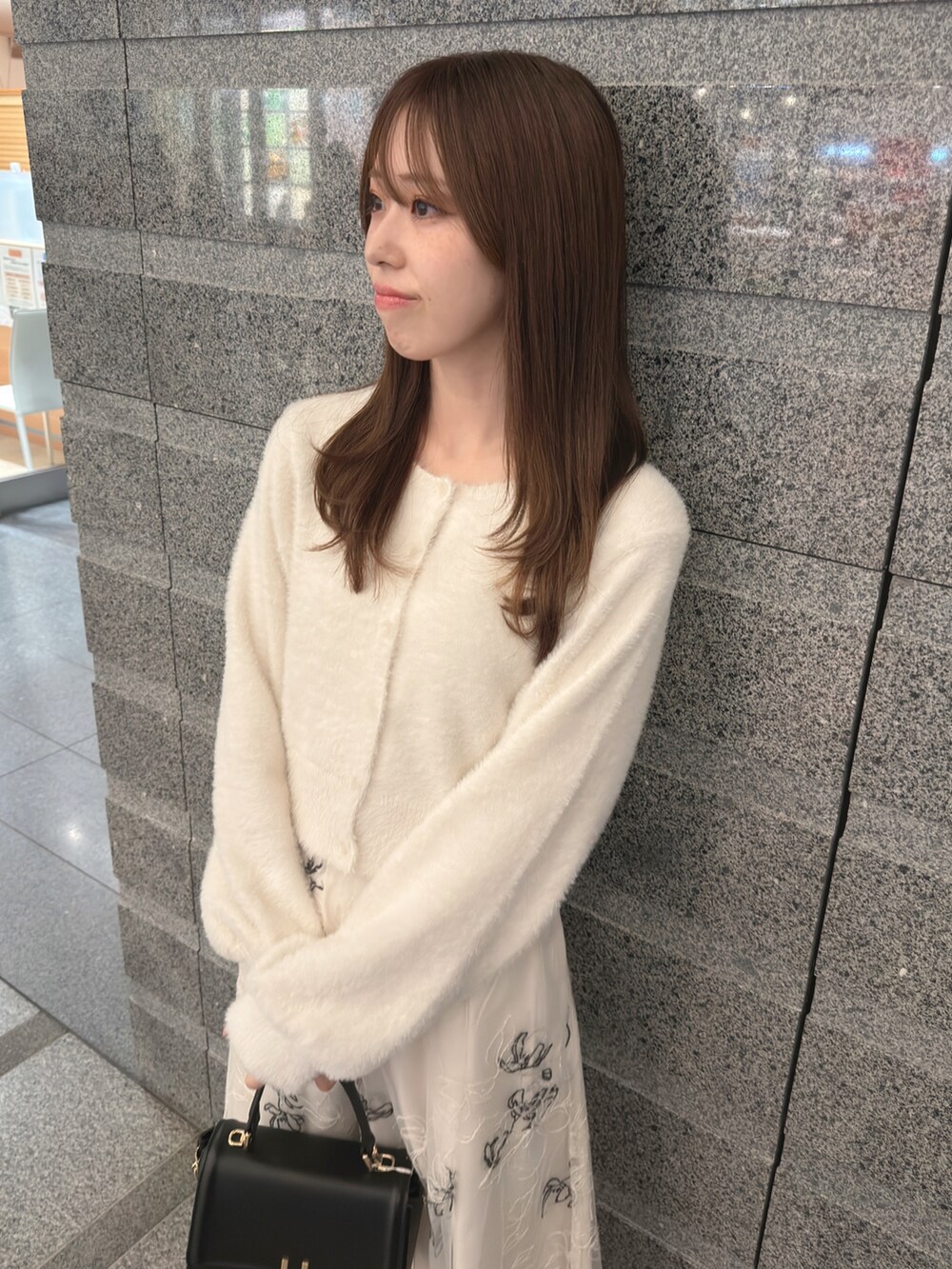 ホワイト系のカーディガン/ボレロ、ホワイト系のスカート、ブラック系のハンドバッグを着用したレディースの秋コーディネートの8枚目の写真