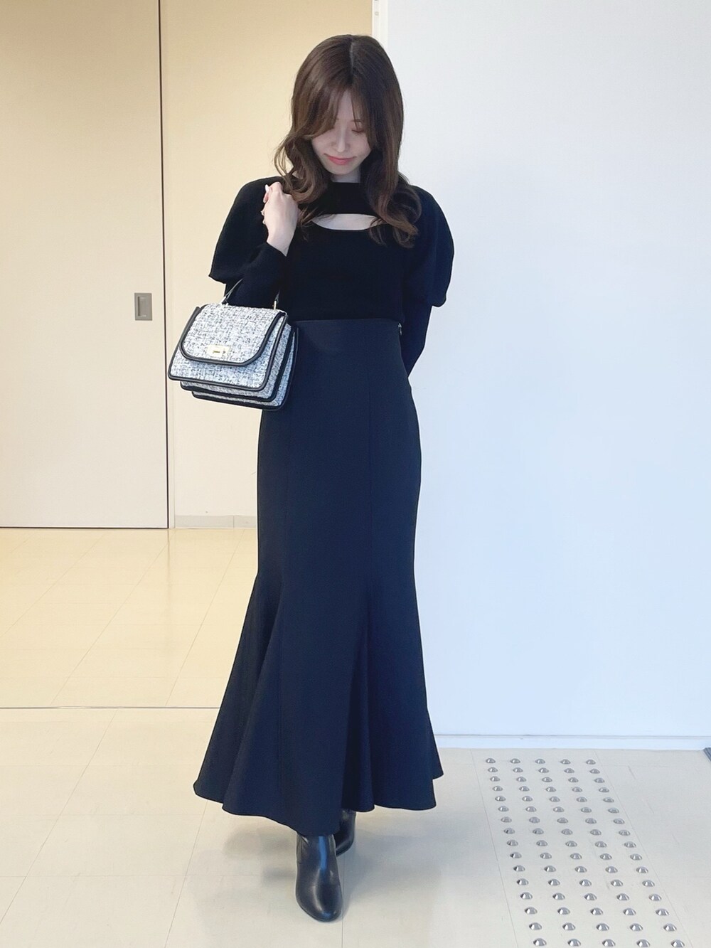 ブラック系のスカート、ブラック系のショルダーバッグ、ブラック系のブーツを着用したレディースの冬コーディネートの2枚目の写真