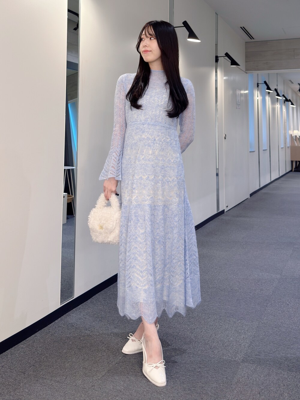 ブルー系のワンピース、ホワイト系のハンドバッグ、ホワイト系のパンプスを着用したレディースの秋コーディネートの5枚目の写真