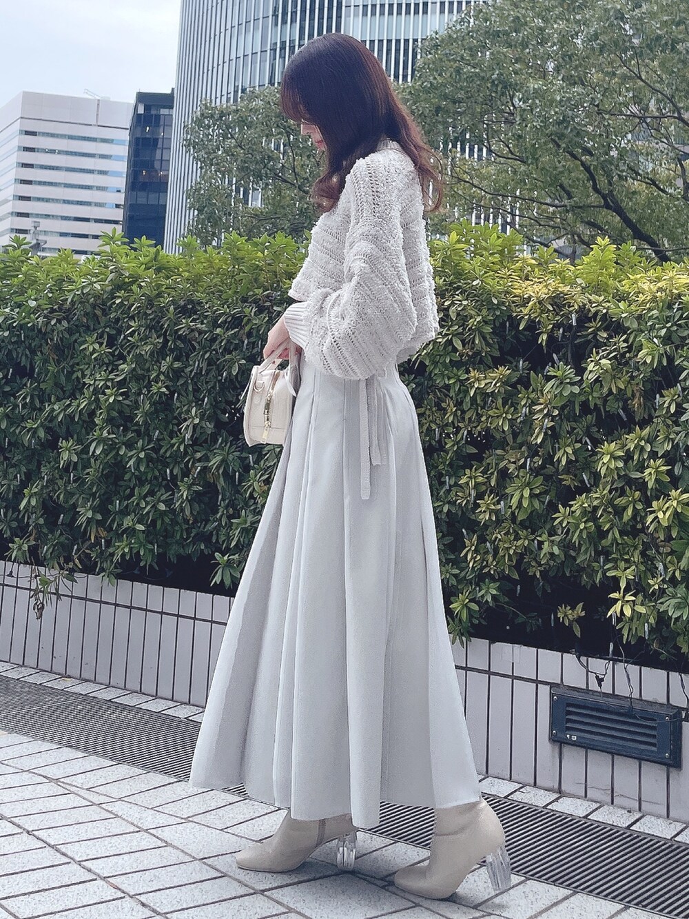 グレー系のニット/セーター、グリーン系のスカート、ホワイト系のハンドバッグを着用したレディースの冬コーディネートの4枚目の写真