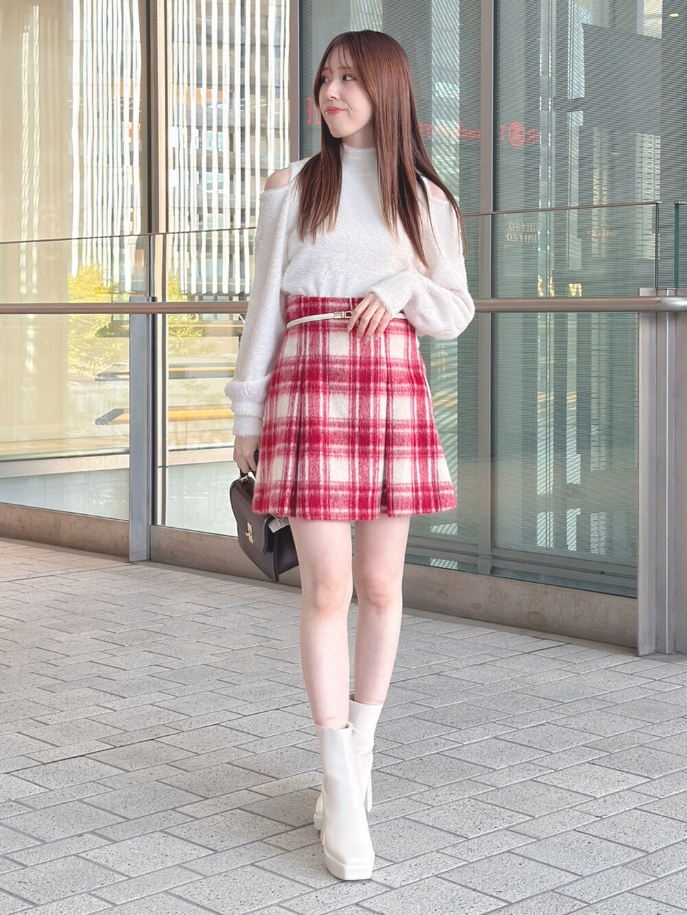 ブラウン系のチェスターコート、ホワイト系のニット/セーター、レッド系のその他パンツを着用したレディースの冬コーディネートの4枚目の写真