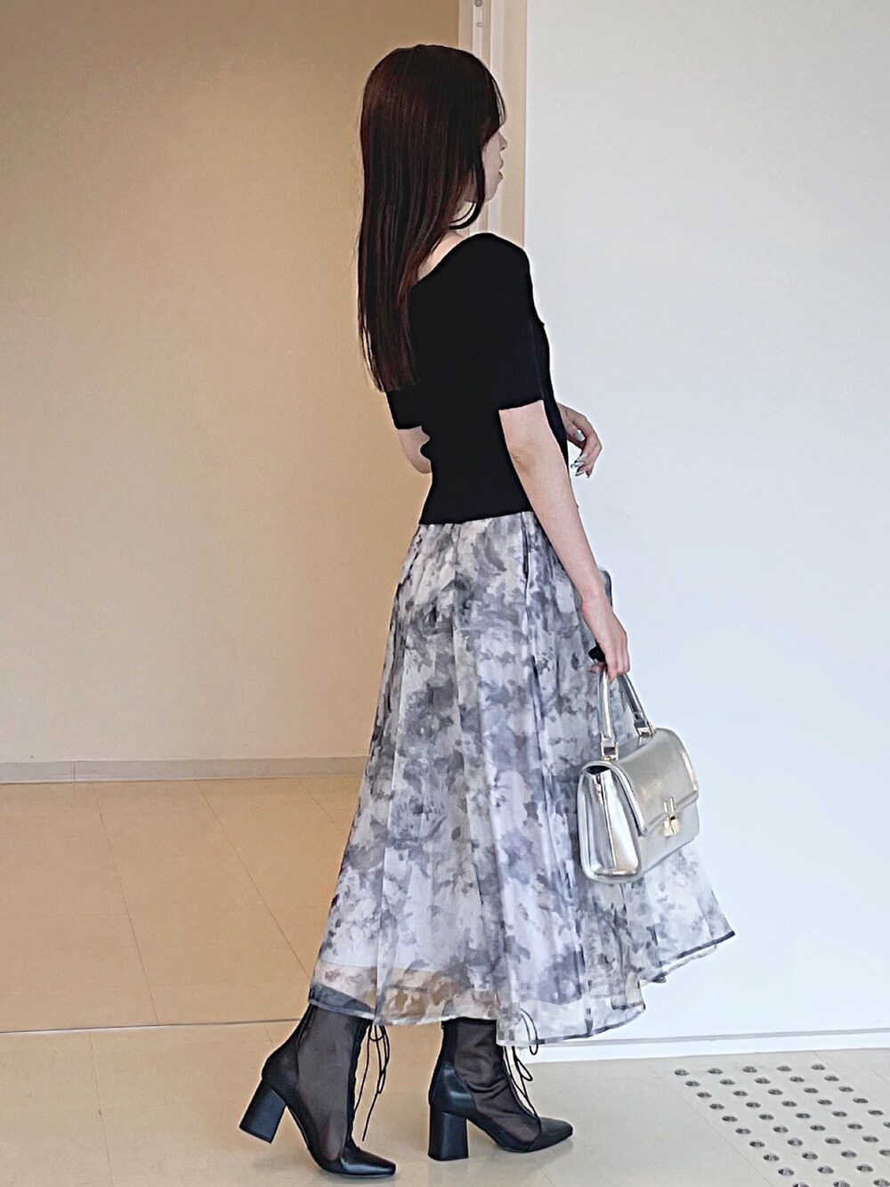 ブラック系のニット/セーター、グレー系のスカート、シルバー系のハンドバッグを着用したレディースの夏コーディネートの4枚目の写真