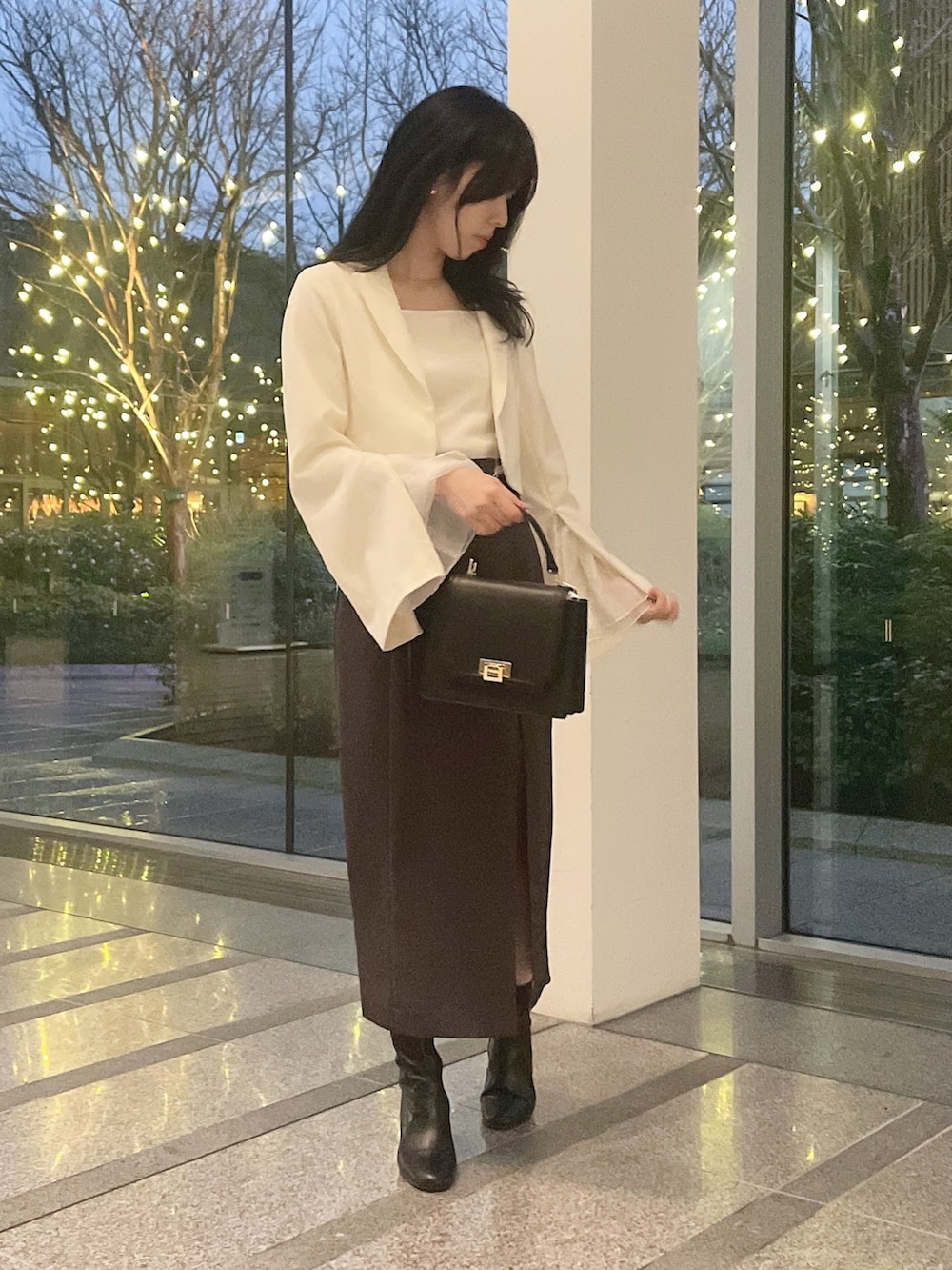 ホワイト系のテーラードジャケット、ホワイト系のニット/セーター、グレー系のスカートを着用したレディースの冬コーディネートの3枚目の写真