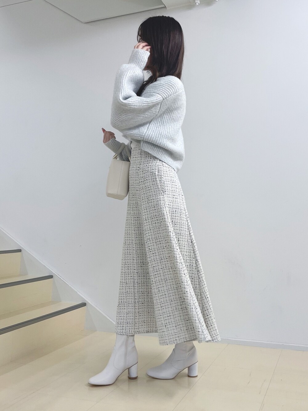 ホワイト系のニット/セーター、ホワイト系のスカート、ホワイト系のハンドバッグを着用したレディースの秋コーディネートの4枚目の写真