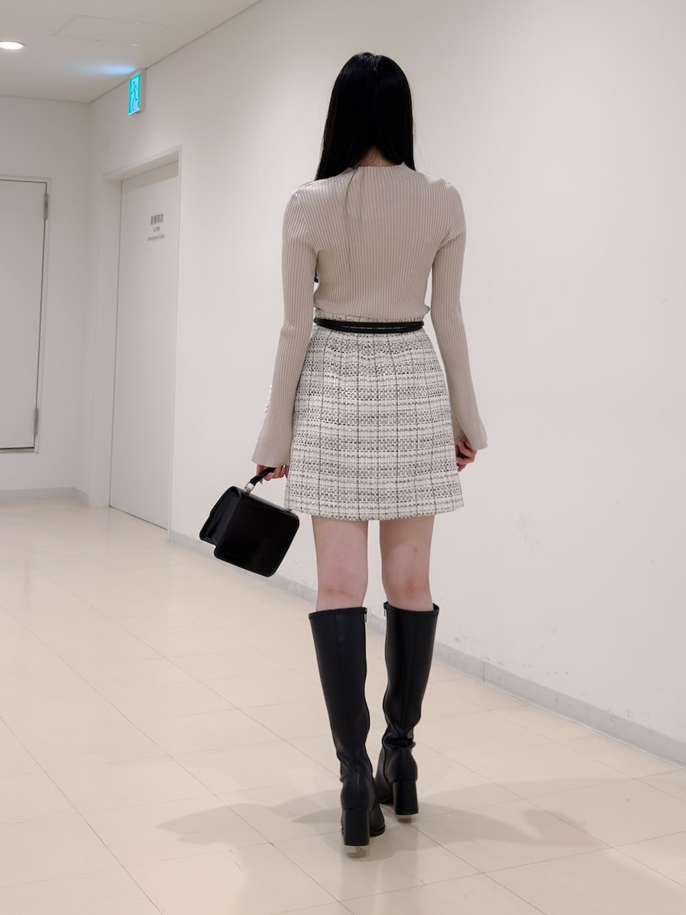 ベージュ系のニット/セーター、ホワイト系のスカート、ブラック系のハンドバッグを着用したレディースの秋コーディネートの5枚目の写真