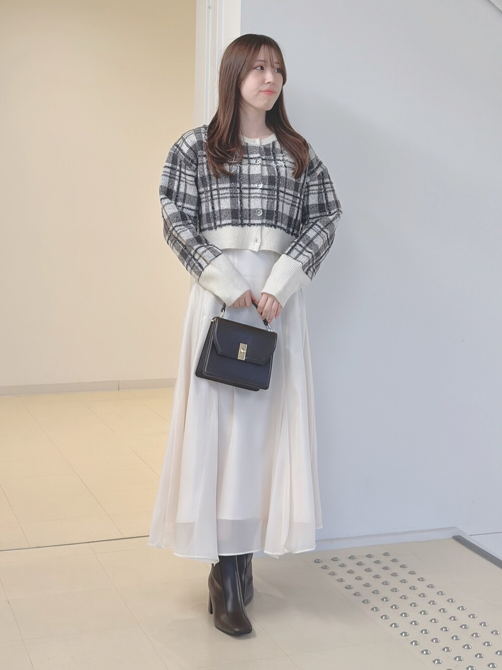ホワイト系のカーディガン/ボレロ、ブラウン系のハンドバッグ、ホワイト系のスカートを着用したレディースの秋コーディネートの2枚目の写真