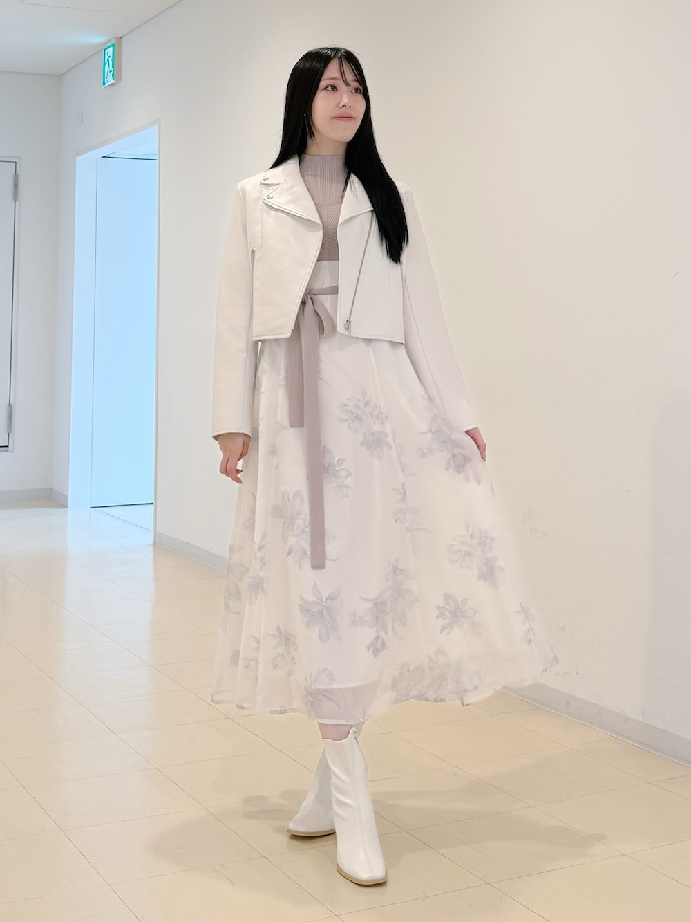 ホワイト系のライダースジャケット、ベージュ系のワンピース、ホワイト系のブーツを着用したレディースの秋コーディネートの2枚目の写真