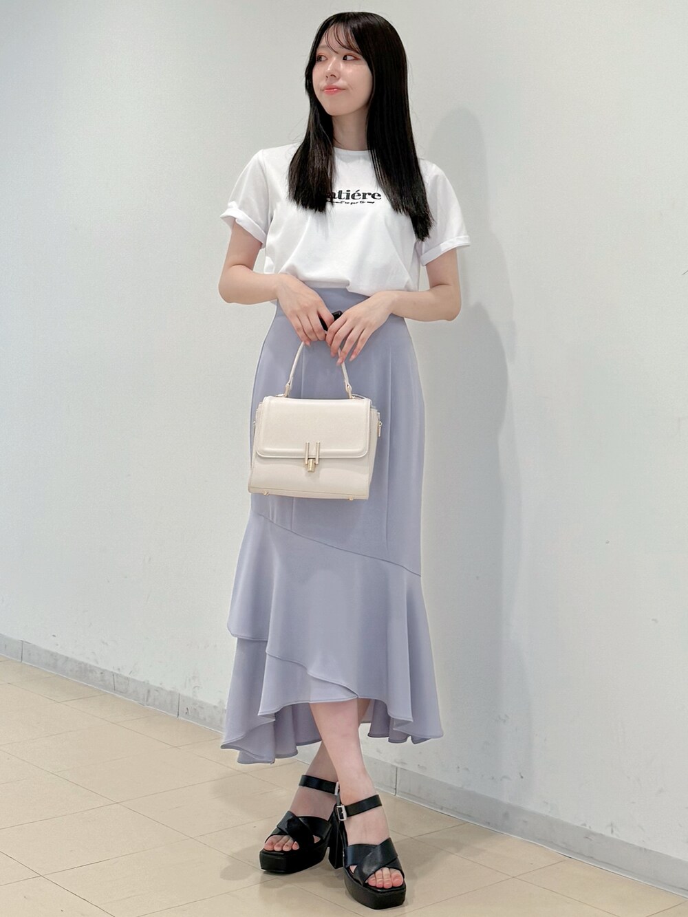 ホワイト系のTシャツ/カットソー、パープル系のスカート、ホワイト系のハンドバッグを着用したレディースの春コーディネートの2枚目の写真