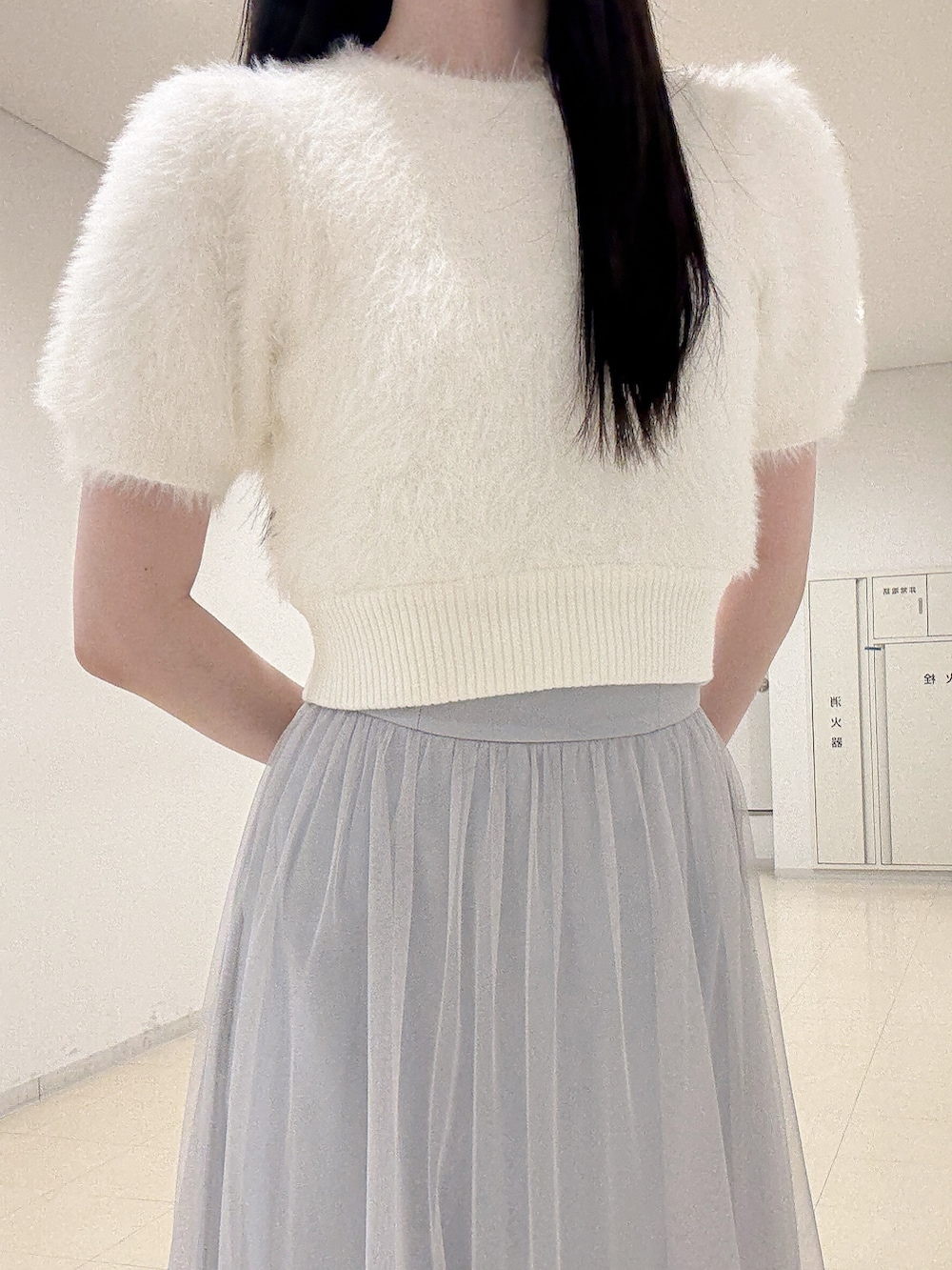 ホワイト系のニット/セーター、ブルー系のスカート、ブラック系のブーツを着用したレディースの夏コーディネートの6枚目の写真