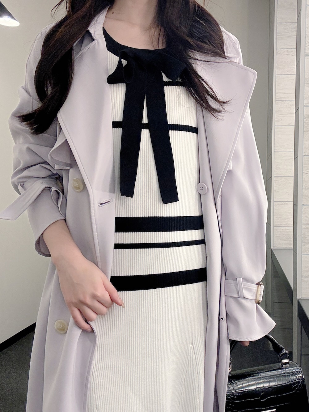 パープル系のトレンチコート、ホワイト系のワンピース、ブラック系のハンドバッグを着用したレディースの冬コーディネートの5枚目の写真