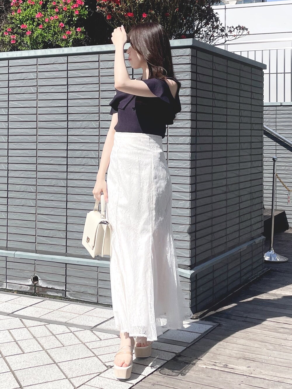 ブルー系のニット/セーター、ホワイト系のスカート、ホワイト系のハンドバッグを着用したレディースの春コーディネートの2枚目の写真