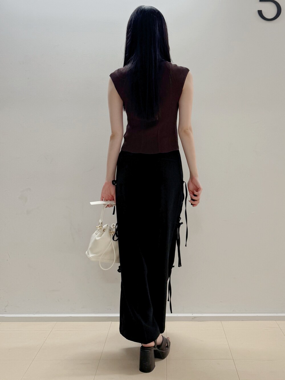 ブラウン系のニット/セーター、ブラック系のその他パンツ、ホワイト系のハンドバッグを着用したレディースの夏コーディネートの5枚目の写真