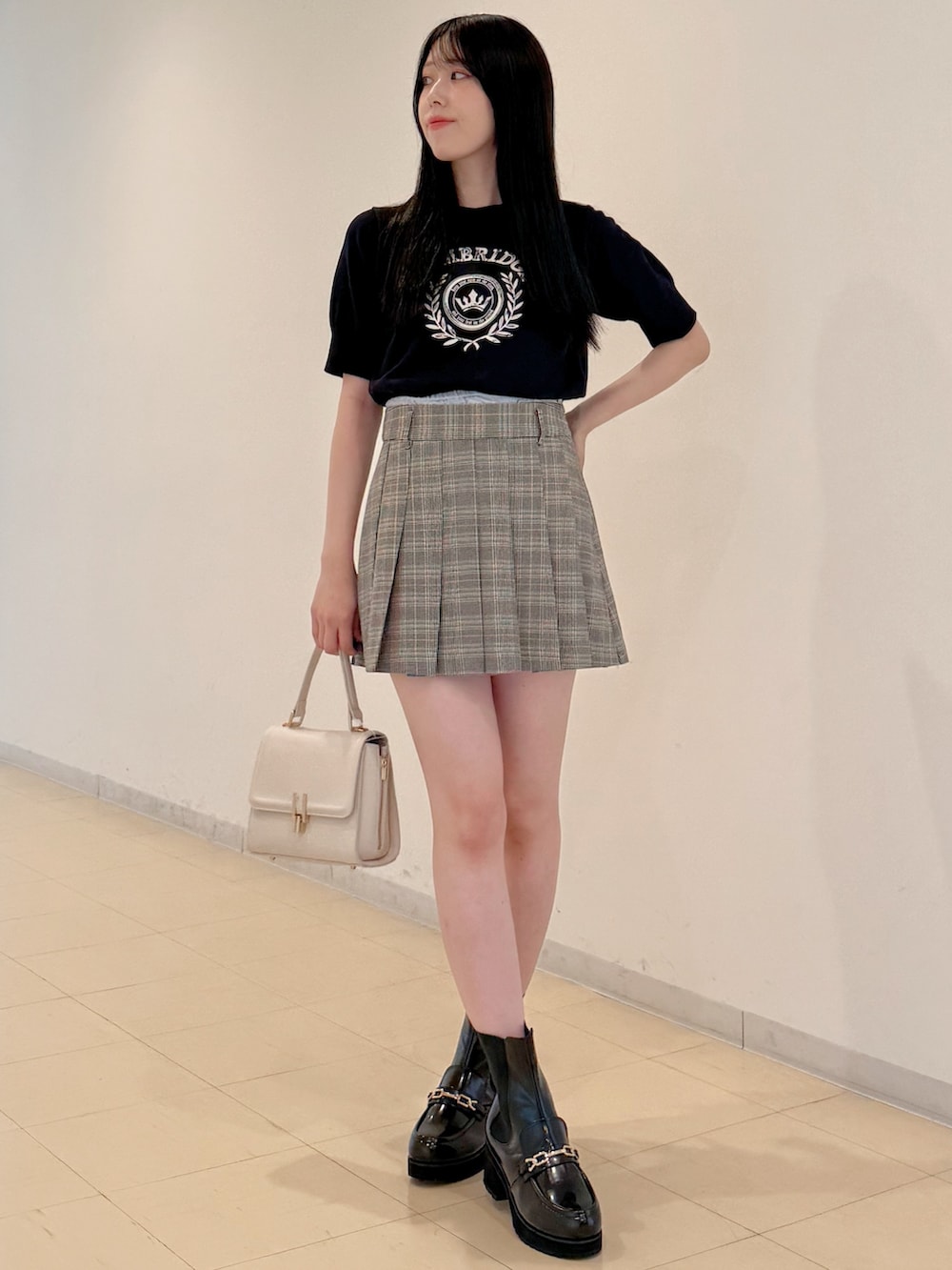 ブルー系のニット/セーター、グレー系のスカート、ホワイト系のハンドバッグを着用したレディースの夏コーディネートの3枚目の写真