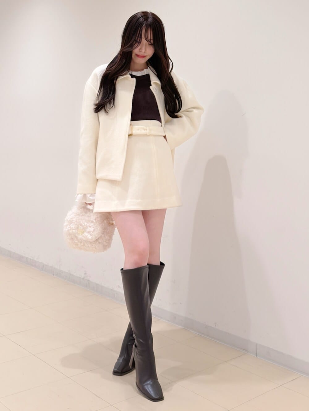 ホワイト系のハンドバッグ、ブラウン系のブーツ、ブラウン系のニット/セーターを着用したレディースの冬コーディネートの3枚目の写真