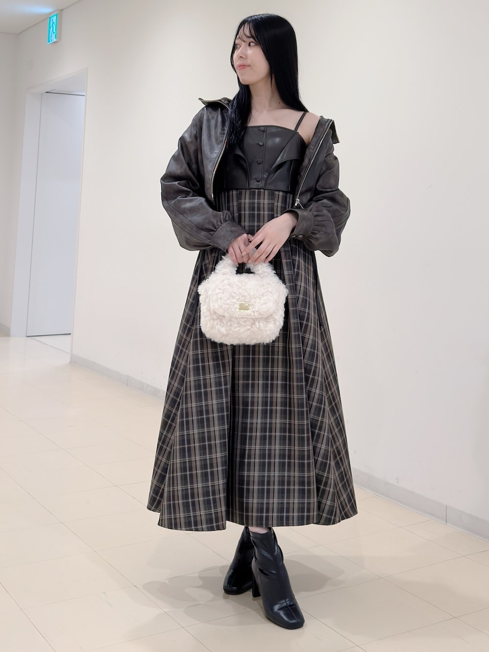 ブラウン系のブルゾン、ホワイト系のハンドバッグ、ブラウン系のワンピースを着用したレディースの秋コーディネートの2枚目の写真