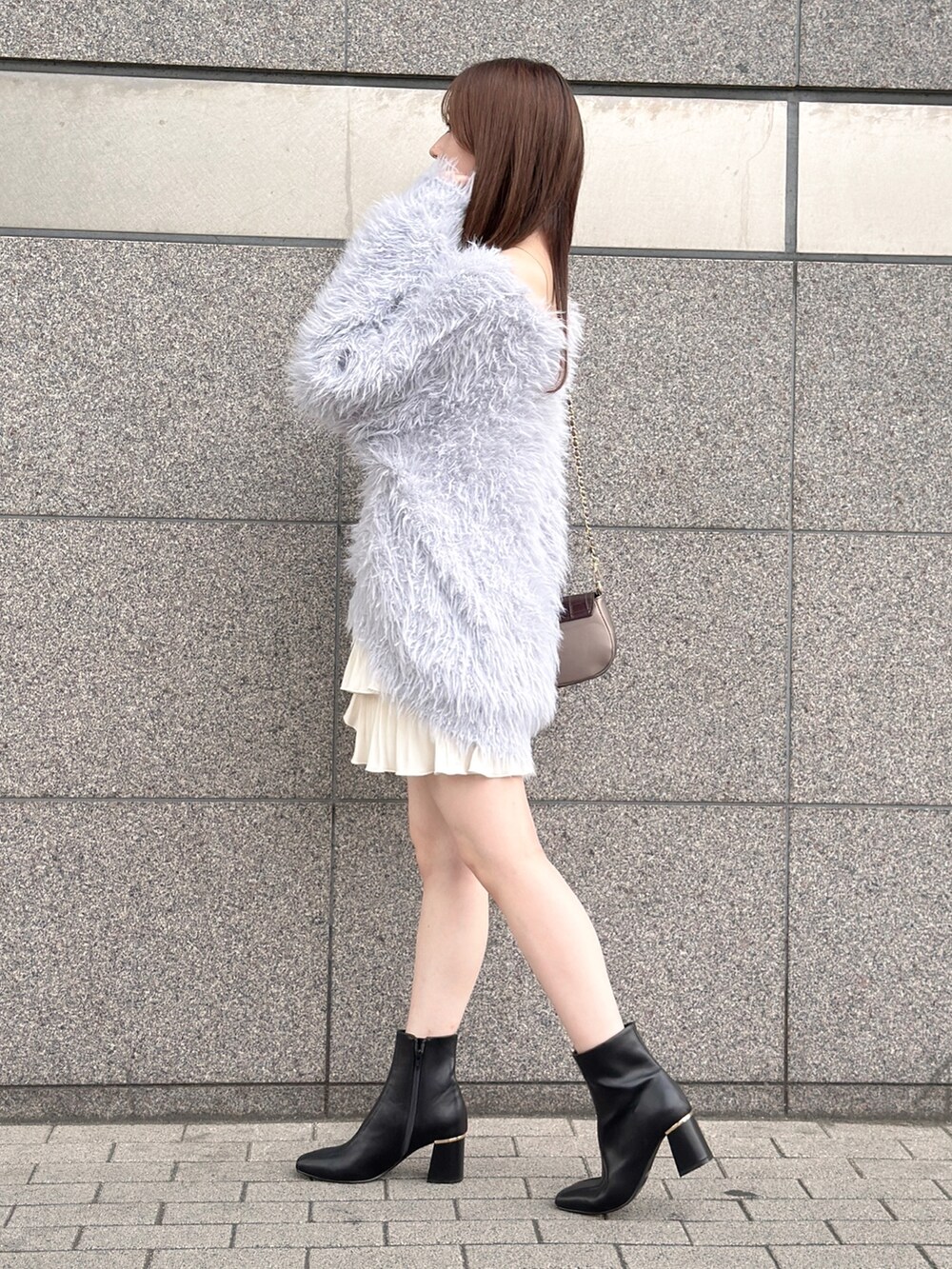 グレー系のニット/セーター、ホワイト系のスカート、ブラック系のブーツを着用したレディースの秋コーディネートの5枚目の写真