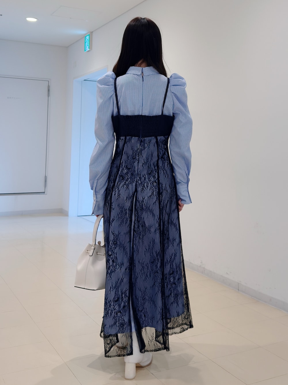 ブルー系のワンピース、ホワイト系のショルダーバッグ、ホワイト系のブーツを着用したレディースの冬コーディネートの4枚目の写真