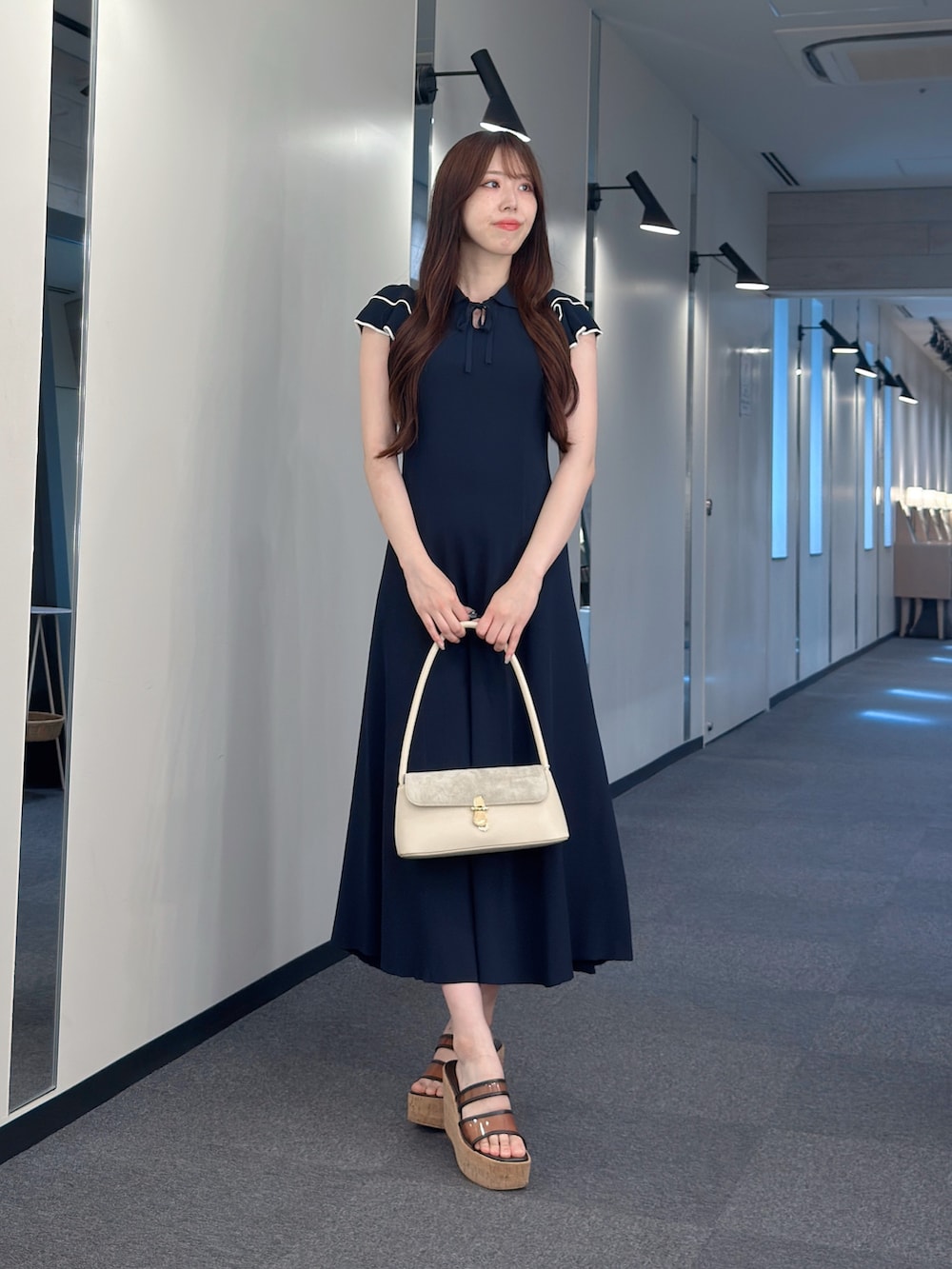 ブルー系のワンピース、ホワイト系のハンドバッグ、ブラウン系のサンダルを着用したレディースの夏コーディネートの2枚目の写真