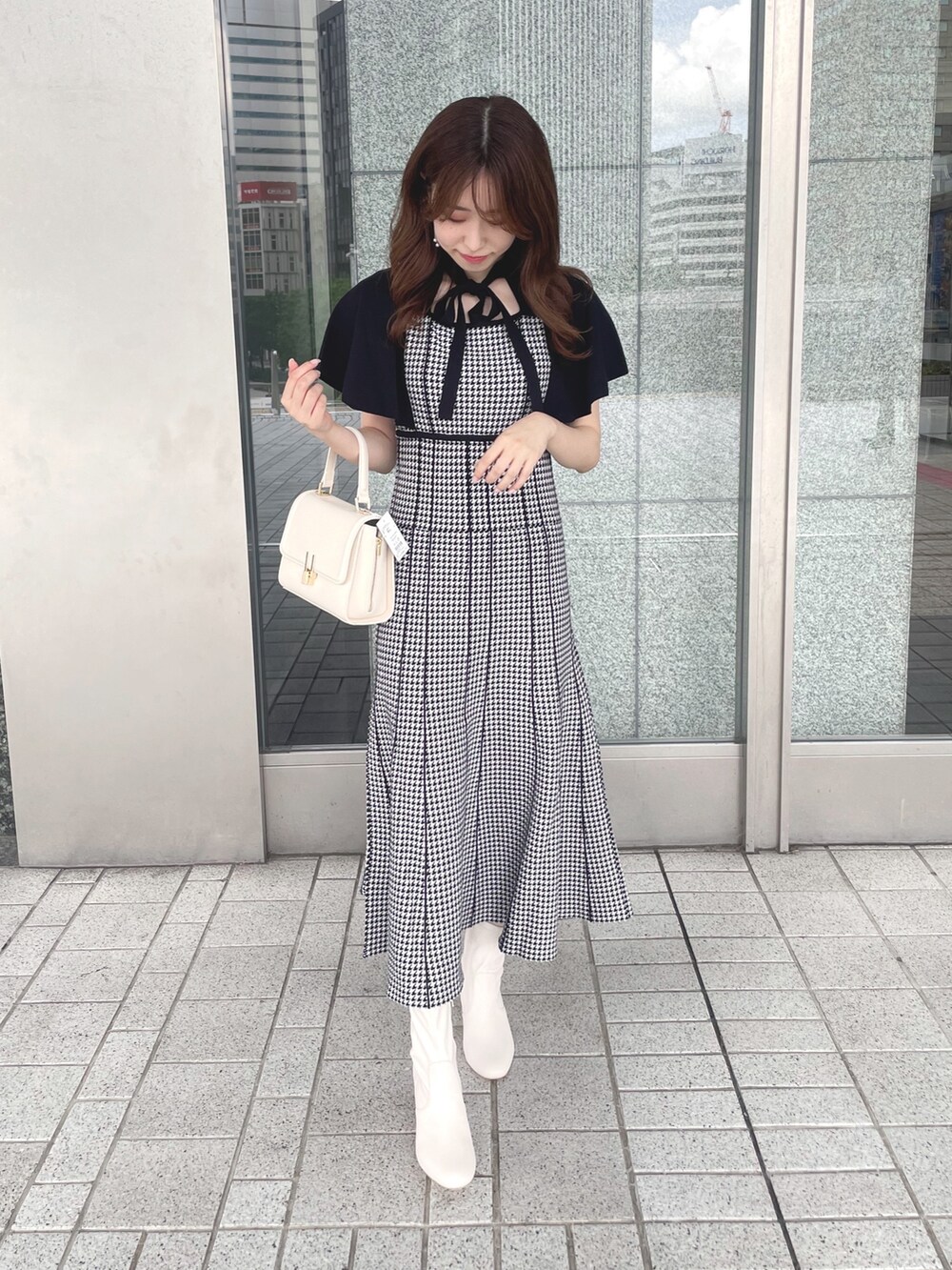 ブラック系のワンピース、ホワイト系のショルダーバッグ、ホワイト系のブーツを着用したレディースの夏コーディネートの3枚目の写真