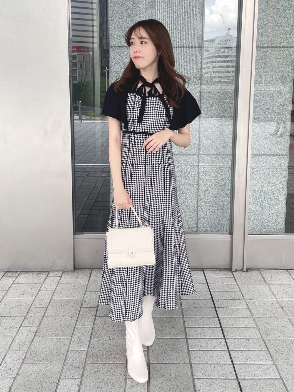 ブラック系のワンピース、ホワイト系のショルダーバッグ、ホワイト系のブーツを着用したレディースの夏コーディネートの2枚目の写真