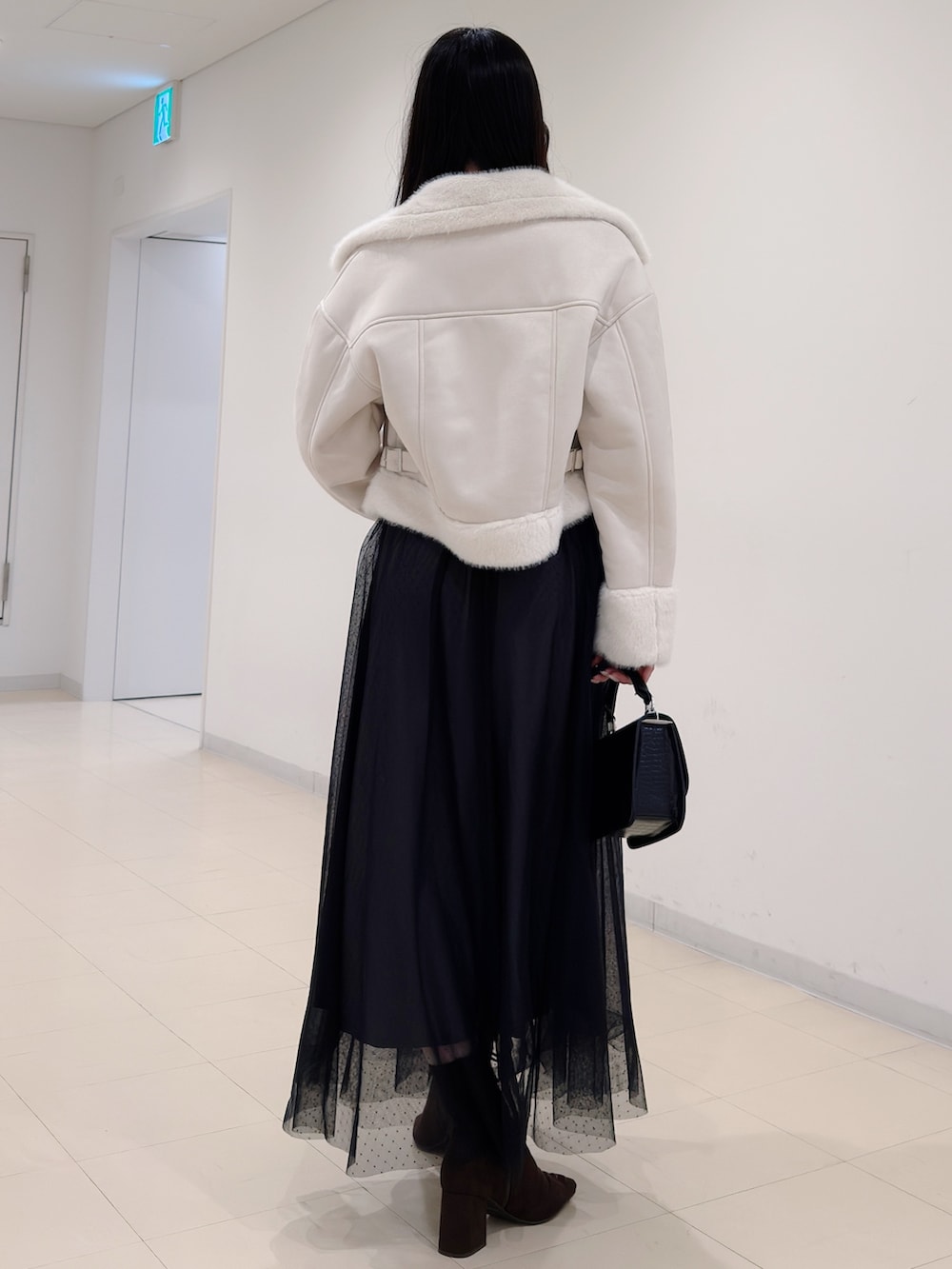 ブラウン系のブーツ、ブラック系のハンドバッグ、ブラック系のワンピースを着用したレディースの秋コーディネートの4枚目の写真