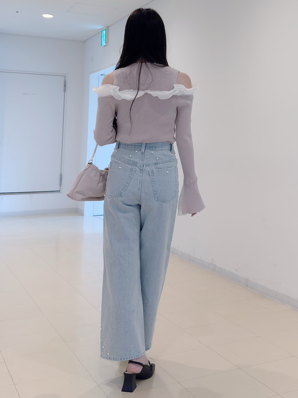 ベージュ系のニット/セーター、ブルー系のデニムパンツ、ピンク系のショルダーバッグを着用したレディースの春コーディネートの4枚目の写真