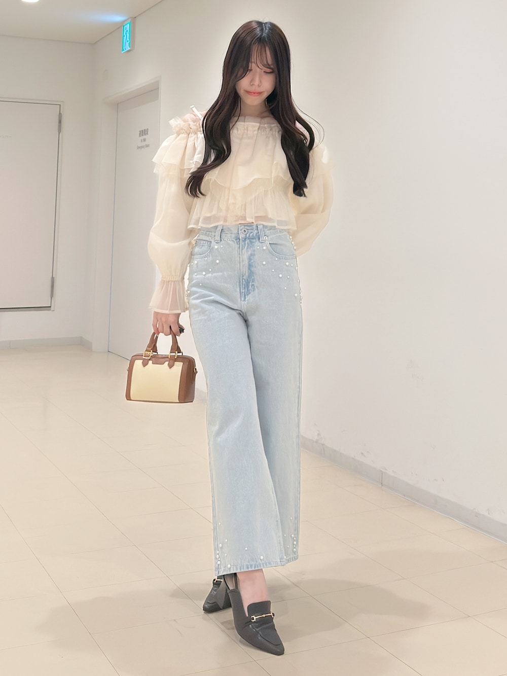 ホワイト系のシャツ/ブラウス、ブルー系のデニムパンツ、ブラウン系のハンドバッグを着用したレディースの春コーディネートの3枚目の写真