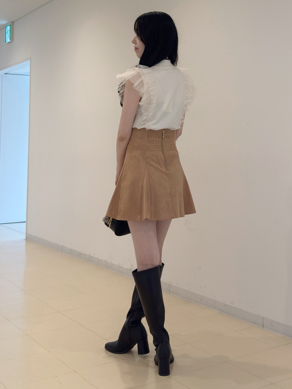 ホワイト系のニット/セーター、ブラック系のハンドバッグ、イエロー系のスカートを着用したレディースの夏コーディネートの5枚目の写真