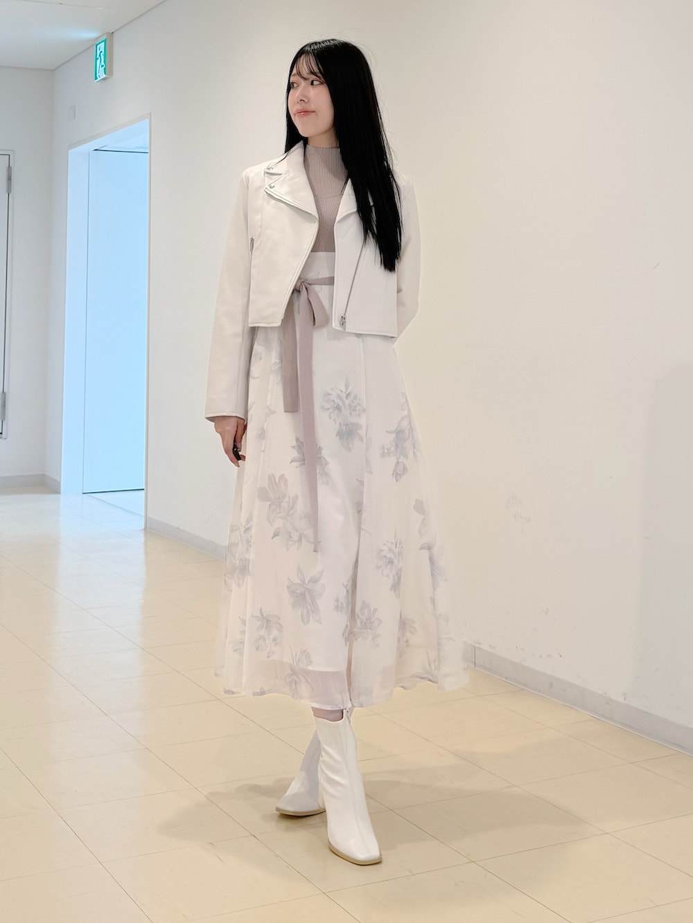 ホワイト系のライダースジャケット、ベージュ系のワンピース、ホワイト系のブーツを着用したレディースの秋コーディネートの3枚目の写真