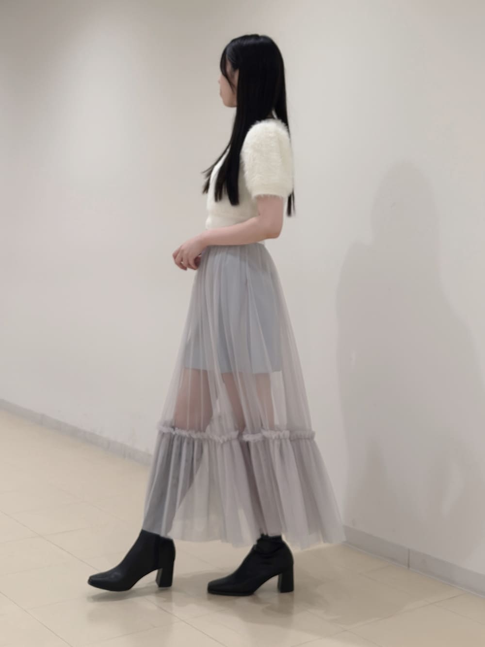 ホワイト系のニット/セーター、ブルー系のスカート、ブラック系のブーツを着用したレディースの夏コーディネートの4枚目の写真