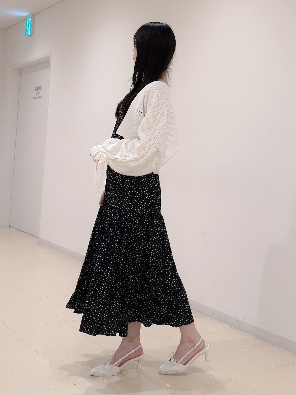 ブラック系のワンピース、ホワイト系のカーディガン/ボレロ、ホワイト系のパンプスを着用したレディースの秋コーディネートの3枚目の写真