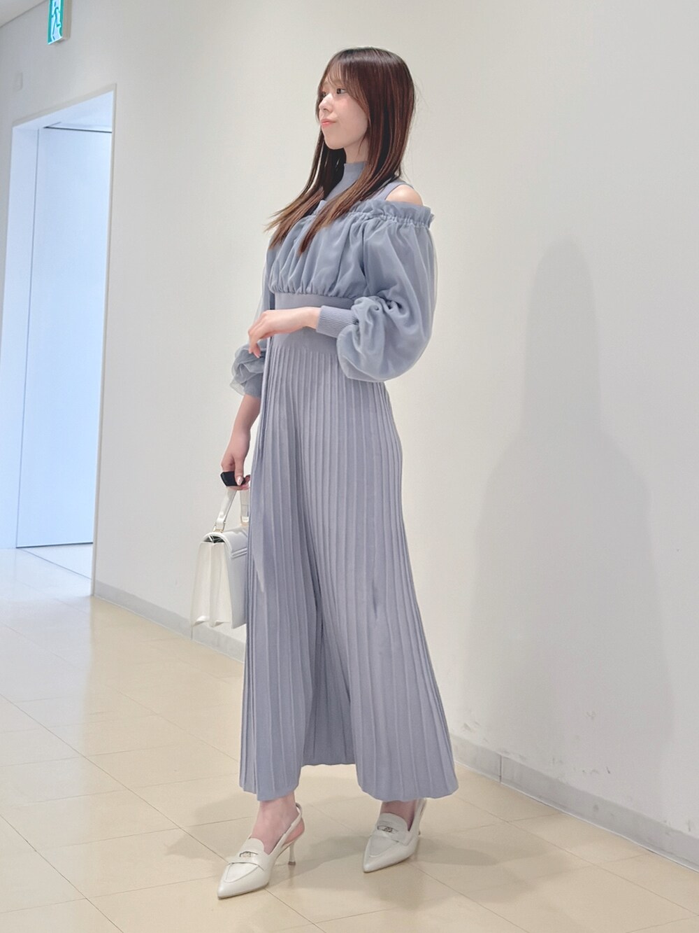 ブルー系のワンピース、ホワイト系のハンドバッグ、ホワイト系のパンプスを着用したレディースの冬コーディネートの4枚目の写真