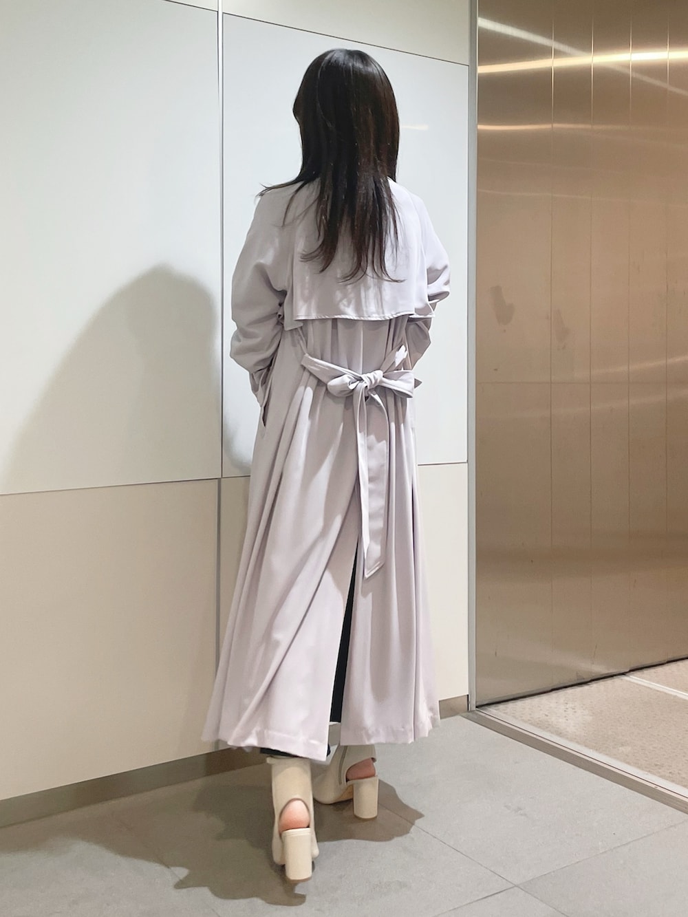 ブラック系のハンドバッグ、パープル系のトレンチコート、ホワイト系のニット/セーターを着用したレディースの冬コーディネートの5枚目の写真