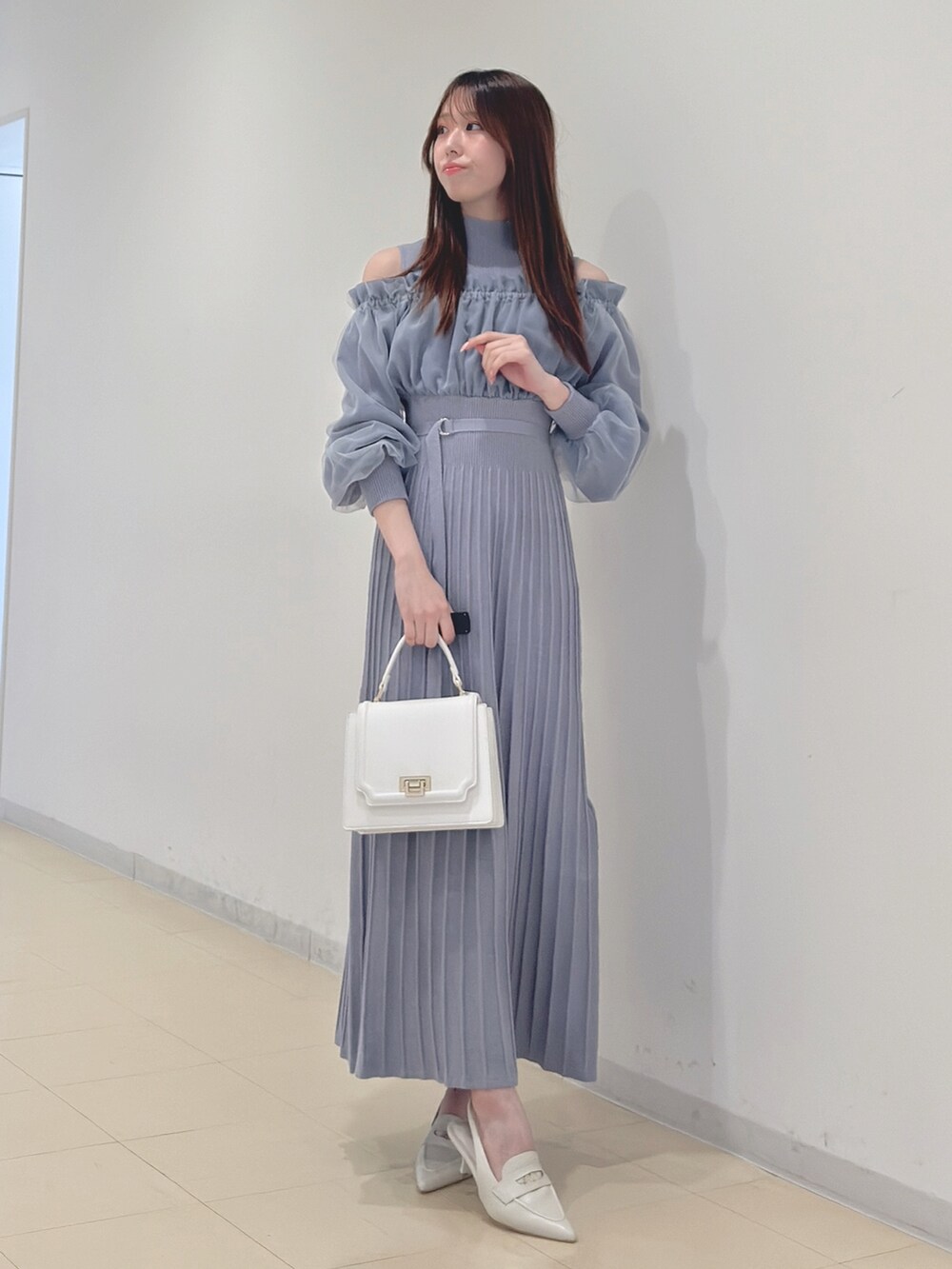 ブルー系のワンピース、ホワイト系のハンドバッグ、ホワイト系のパンプスを着用したレディースの冬コーディネートの3枚目の写真