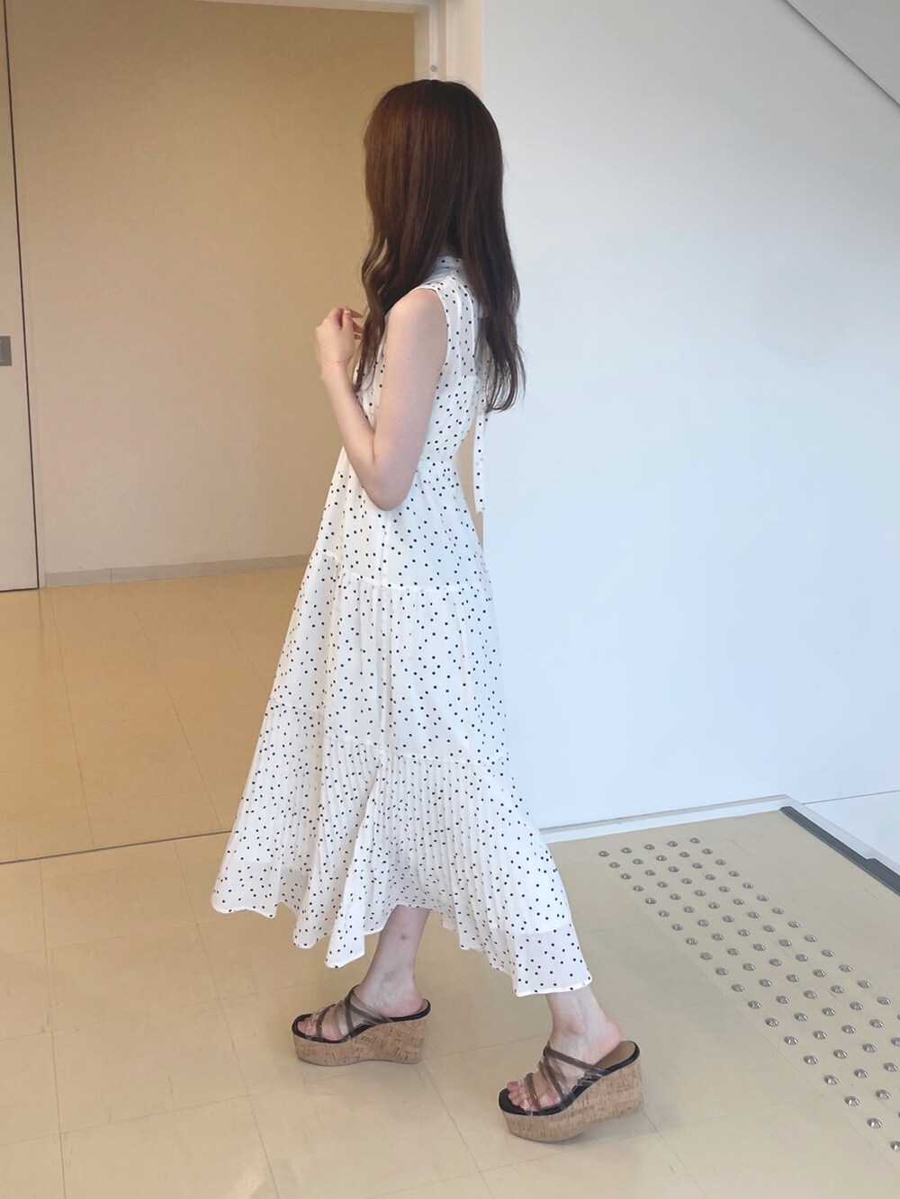 ホワイト系のワンピース、ブラック系のサンダル、シルバー系のイヤリングを着用したレディースの夏コーディネートの3枚目の写真