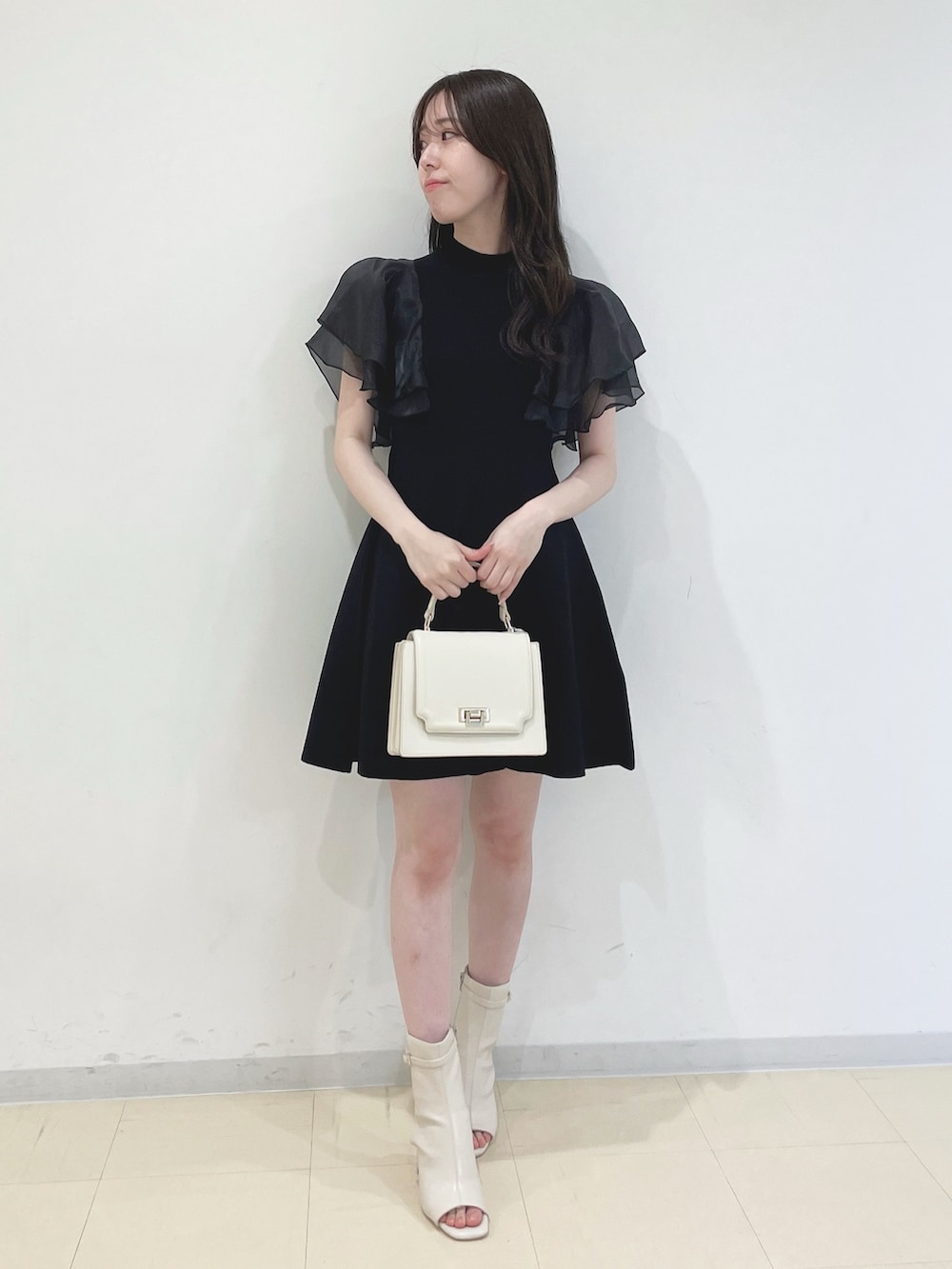 ブラック系のワンピース、ホワイト系のハンドバッグ、ホワイト系のブーツを着用したレディースの春コーディネートの4枚目の写真