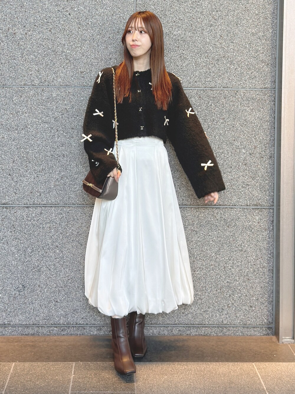 ブラック系のカーディガン/ボレロ、ホワイト系のスカート、ブラウン系のハンドバッグを着用したレディースの秋コーディネートの2枚目の写真