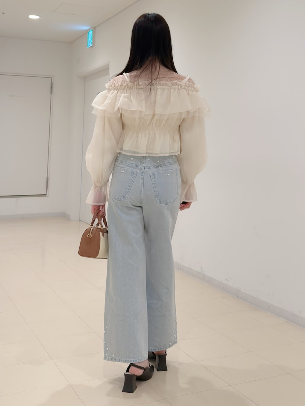 ホワイト系のシャツ/ブラウス、ブルー系のデニムパンツ、ブラウン系のハンドバッグを着用したレディースの春コーディネートの5枚目の写真