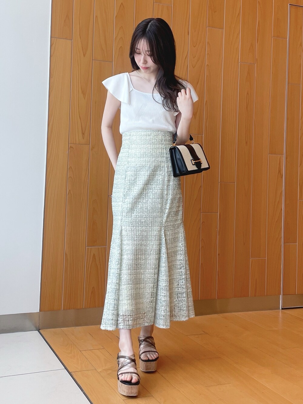 ベージュ系のシャツ/ブラウス、ホワイト系のニット/セーター、グリーン系のスカートを着用したレディースの春コーディネートの6枚目の写真