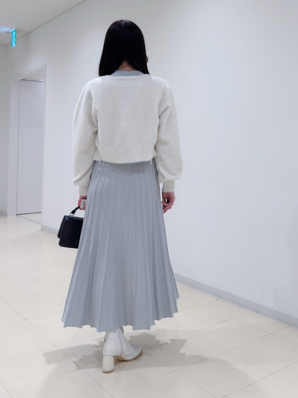 ブラック系のハンドバッグ、ホワイト系のブーツ、ホワイト系のカーディガン/ボレロを着用したレディースの冬コーディネートの4枚目の写真