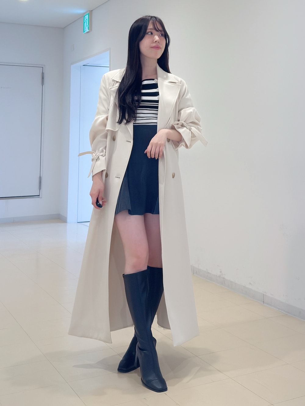 ホワイト系のトレンチコート、その他のニット/セーター、グレー系のスカートを着用したレディースの冬コーディネートの2枚目の写真