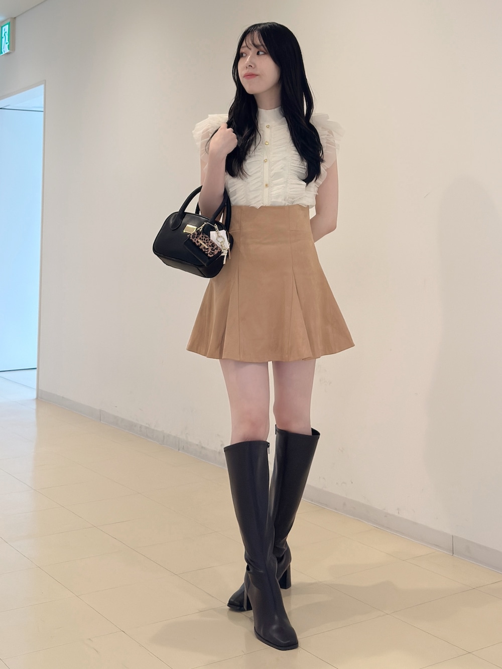 ホワイト系のニット/セーター、ブラック系のハンドバッグ、イエロー系のスカートを着用したレディースの夏コーディネートの2枚目の写真