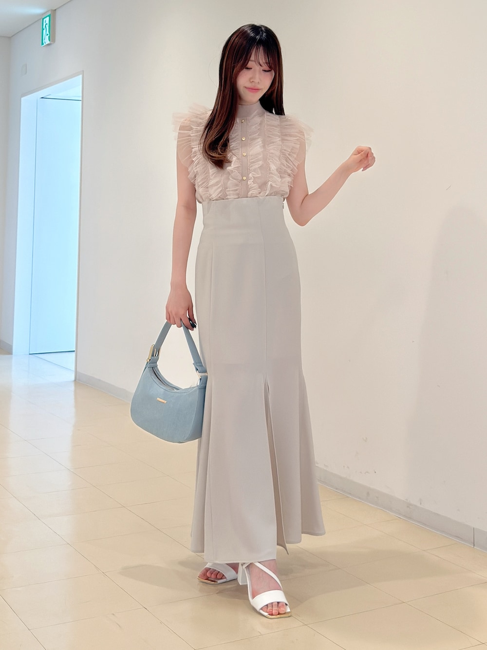 ピンク系のニット/セーター、ホワイト系のスカート、ブルー系のショルダーバッグを着用したレディースの春コーディネートの2枚目の写真